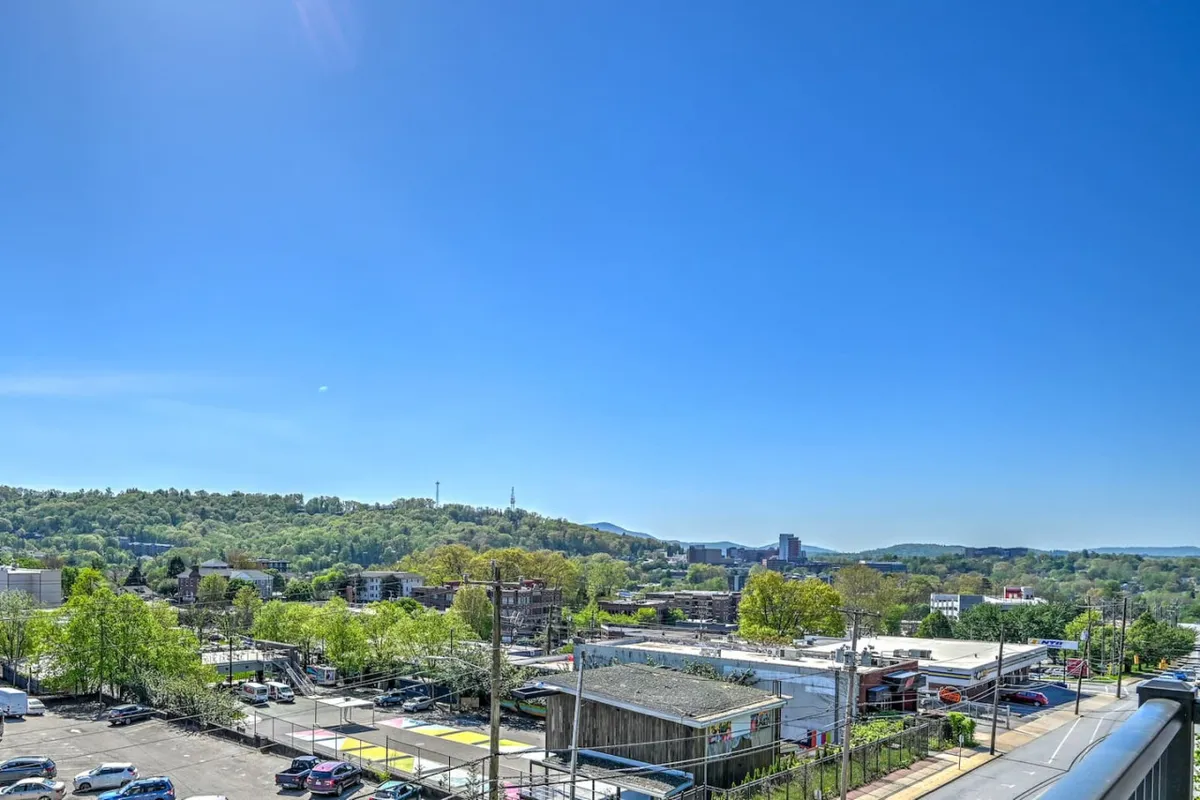 A panoramic view of Asheville’s city skyline with distant hills and a bright blue sky. The vibrant cityscape captures both the lively downtown area and the scenic natural backdrop that frames the city.