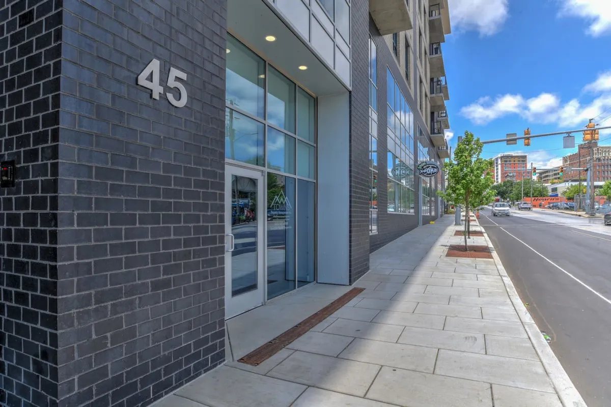 This image showcases the building's modern facade, emphasizing the large windows and prominent address number 45. The sidewalk and traffic lights at the entrance lend an urban, accessible atmosphere perfect for first impressions.